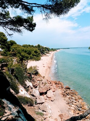 A coastal landscape with a rocky beach, clear blue sea, and dense greenery. - MAGNIFICENT CHALET, 5 NIMUTOS FROM THE BEACH, WITH POOL, TERRACE AND WIFI. (Miami Platja)