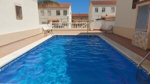 A swimming pool with clear blue water, surrounded by a white wall and a balcony with chairs. - MAGNIFICENT CHALET, 5 NIMUTOS FROM THE BEACH, WITH POOL, TERRACE AND WIFI. (Miami Platja)