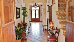 Un corridoio con porte in legno, pavimento piastrellato e una scala con ringhiere decorate.