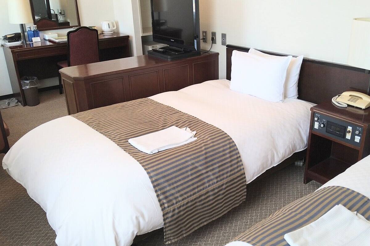 Ein Hotelzimmer mit Bett, Schreibtisch, Fernseher und Telefon.