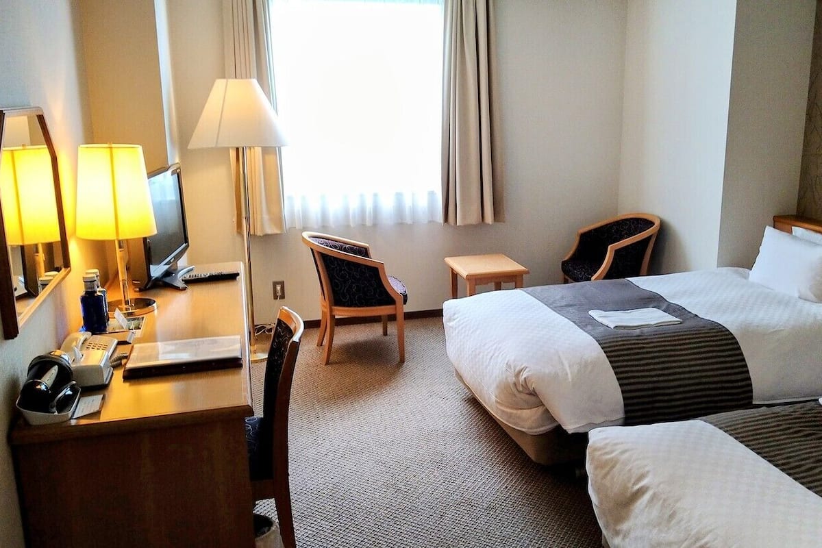 Ein Hotelzimmer mit Bett, Schreibtisch, Stuhl und Lampe.