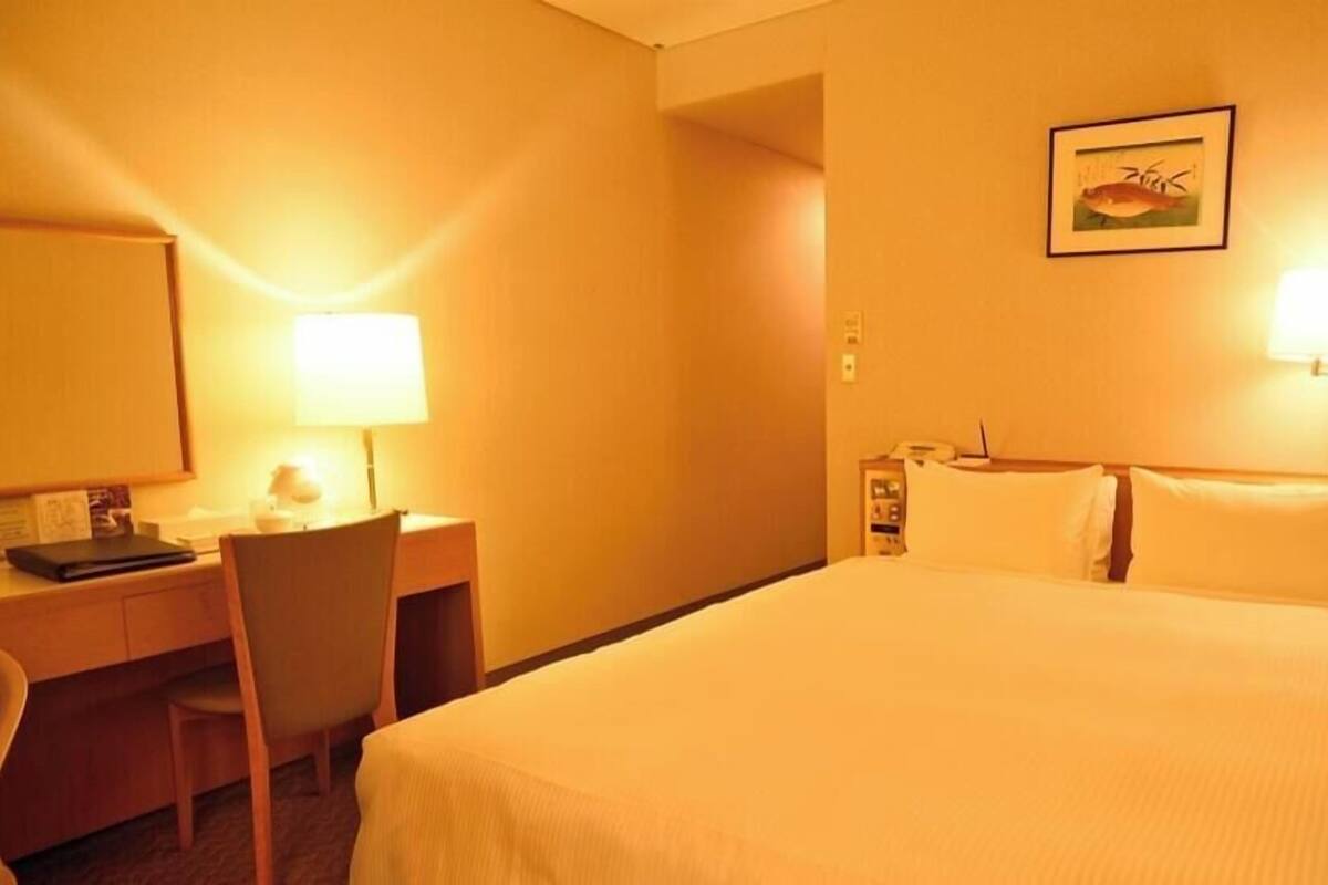 Ein Hotelzimmer mit Bett, Schreibtisch, Stuhl und Lampen.