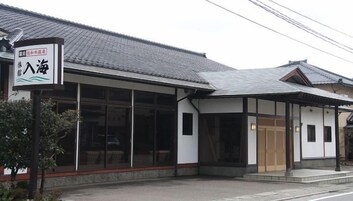 Un edificio japonés tradicional con un cartel, ventanas amplias y tejado de tejas.