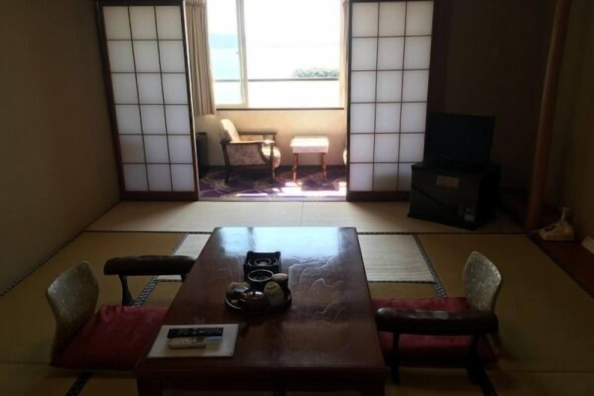A traditional Japanese room with tatami flooring, a low table, and a television.