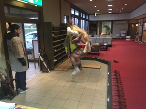 Un vestíbulo de hotel con alfombra roja, un mostrador de recepción y un área de estar.