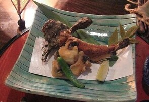 Un plato con mariscos, que incluye un pescado entero, camarones y una cuña de limón.