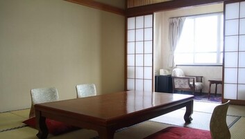 Una habitación tradicional japonesa con suelo de tatami, una mesa de madera baja y un panel shoji.
