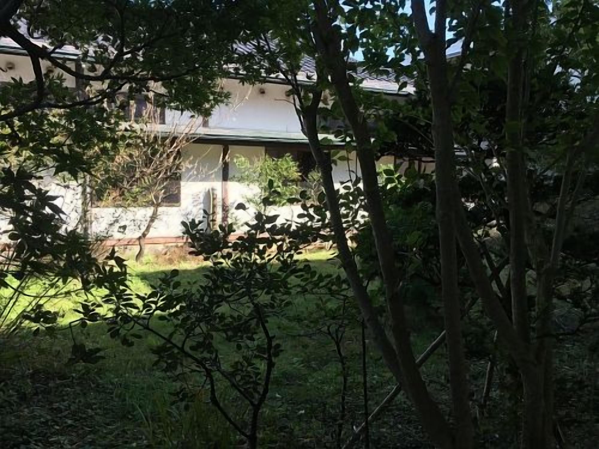 A building with a green roof, surrounded by trees and a grassy area.