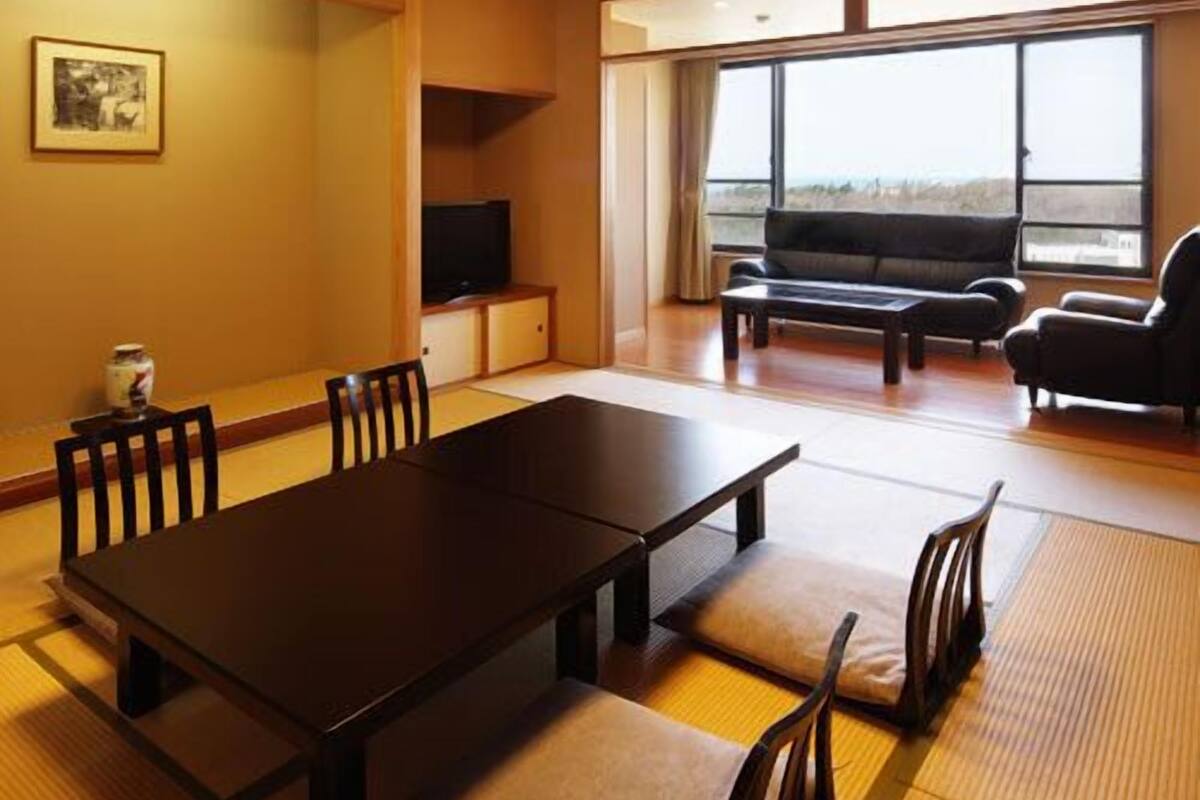 A room with a dining table, chairs, a sofa, and a television.