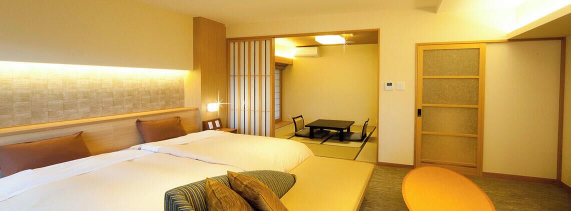 A hotel room with a bed, a small table, and a seating area.