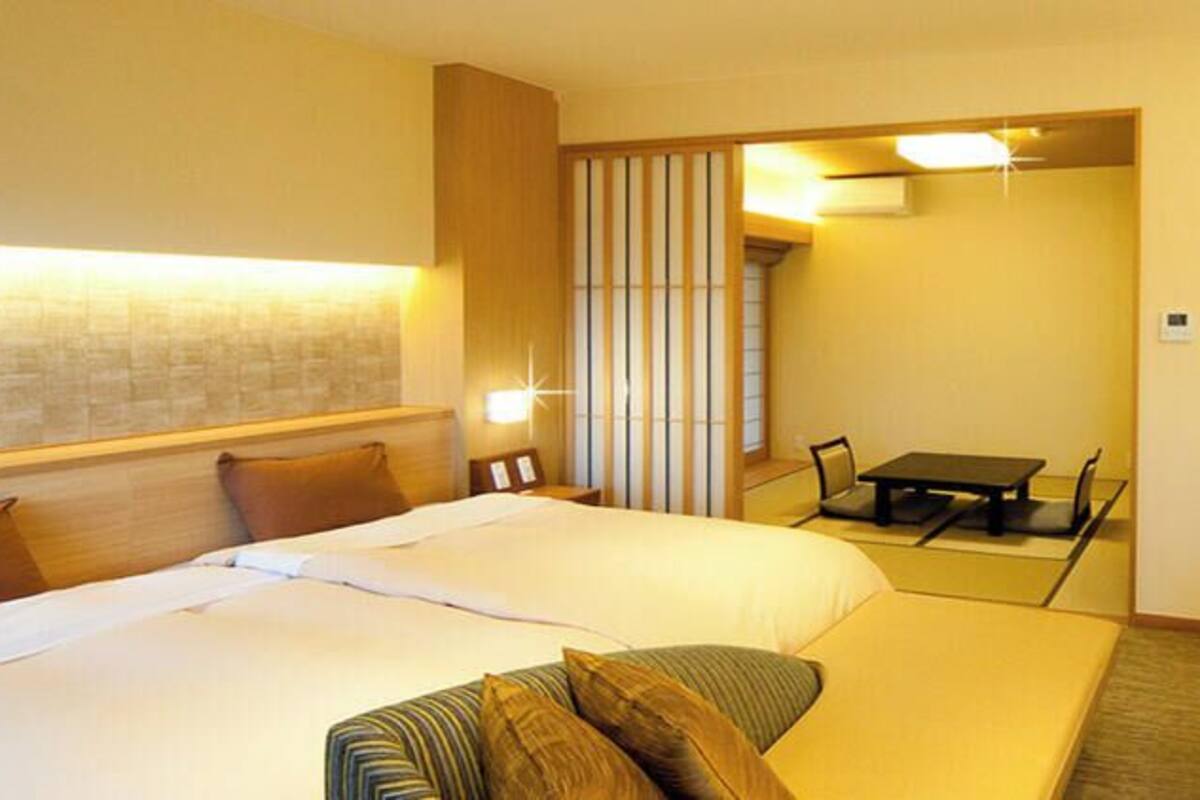 A hotel room with a bed, a small table, and a seating area.