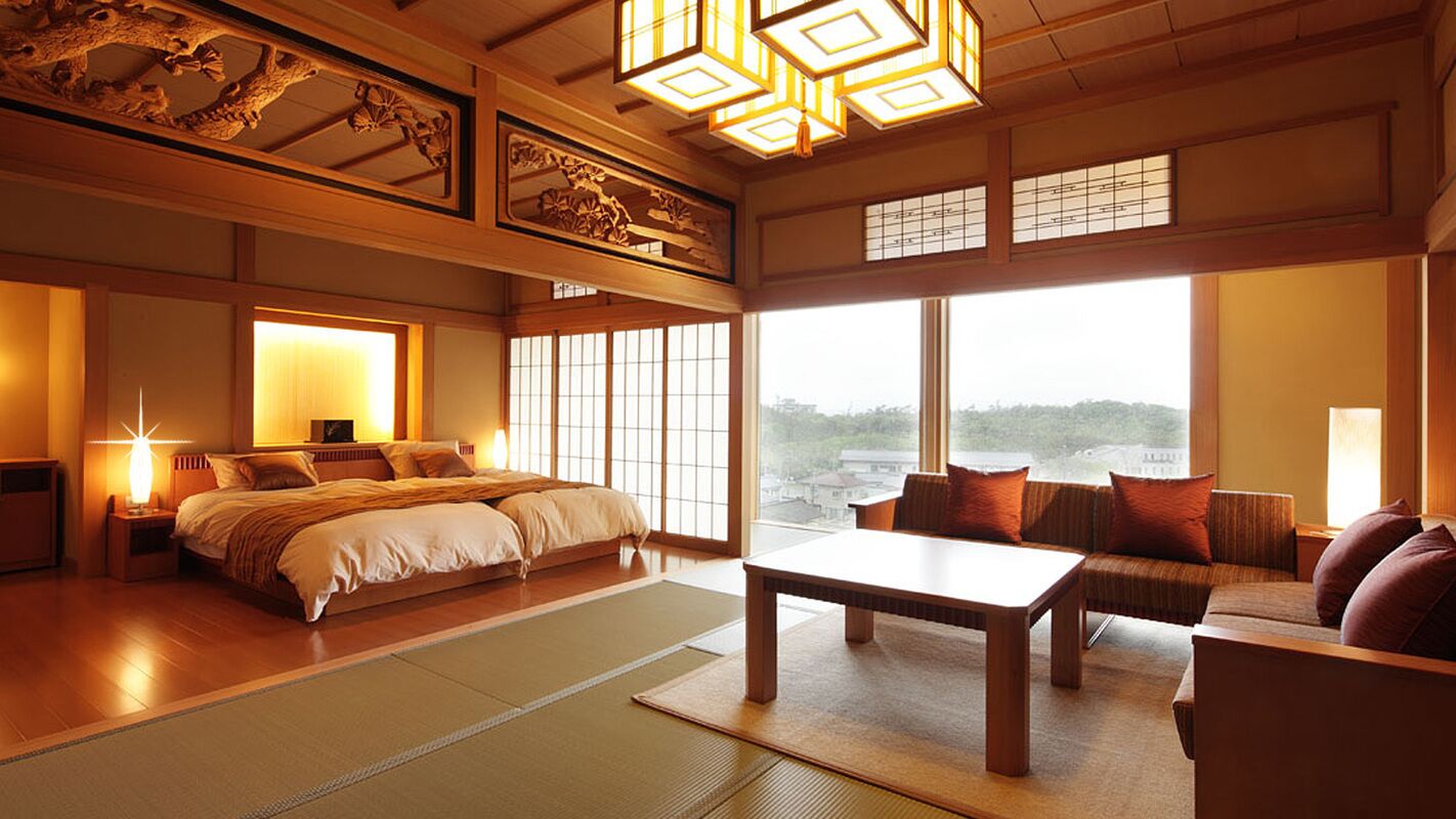 A traditional Japanese-style room with tatami flooring, a low wooden bed, a sofa, and a table.