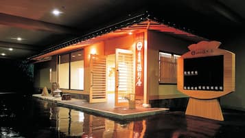 Un edificio tradizionale in stile giapponese, con facciata in legno, scorrevole e una piccola area esterna con posti a sedere.
