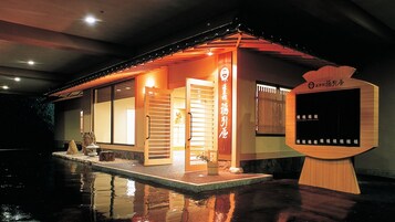 A traditional Japanese-style building with a wooden exterior, a sliding door, and a small outdoor seating area.