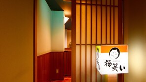 Un couloir doté de portes coulissantes traditionnelles japonaises et d’une enseigne avec des caractères japonais.