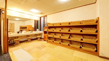 A bathroom with a sink, mirror, and shelves with baskets.
