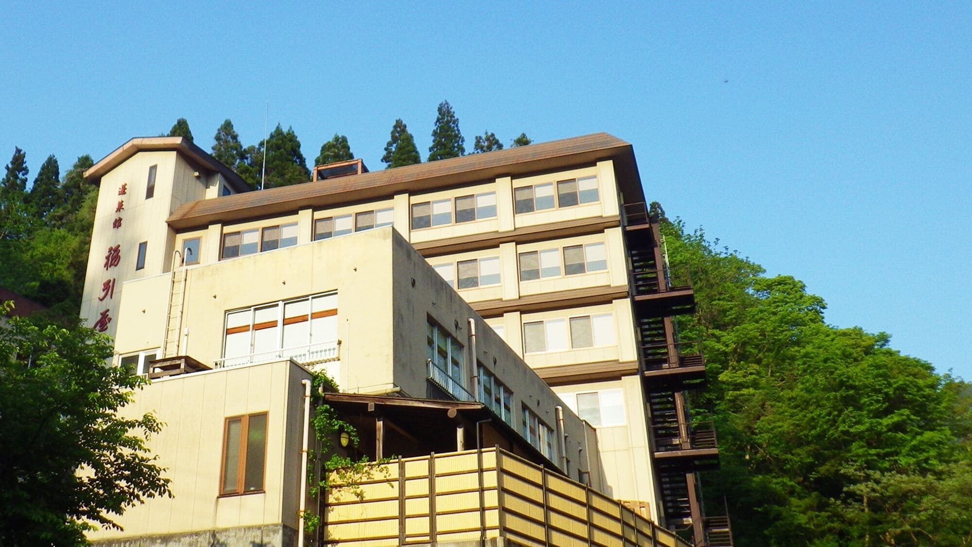 A multi-story building with a flat roof, large windows, and a visible staircase on the right side.
