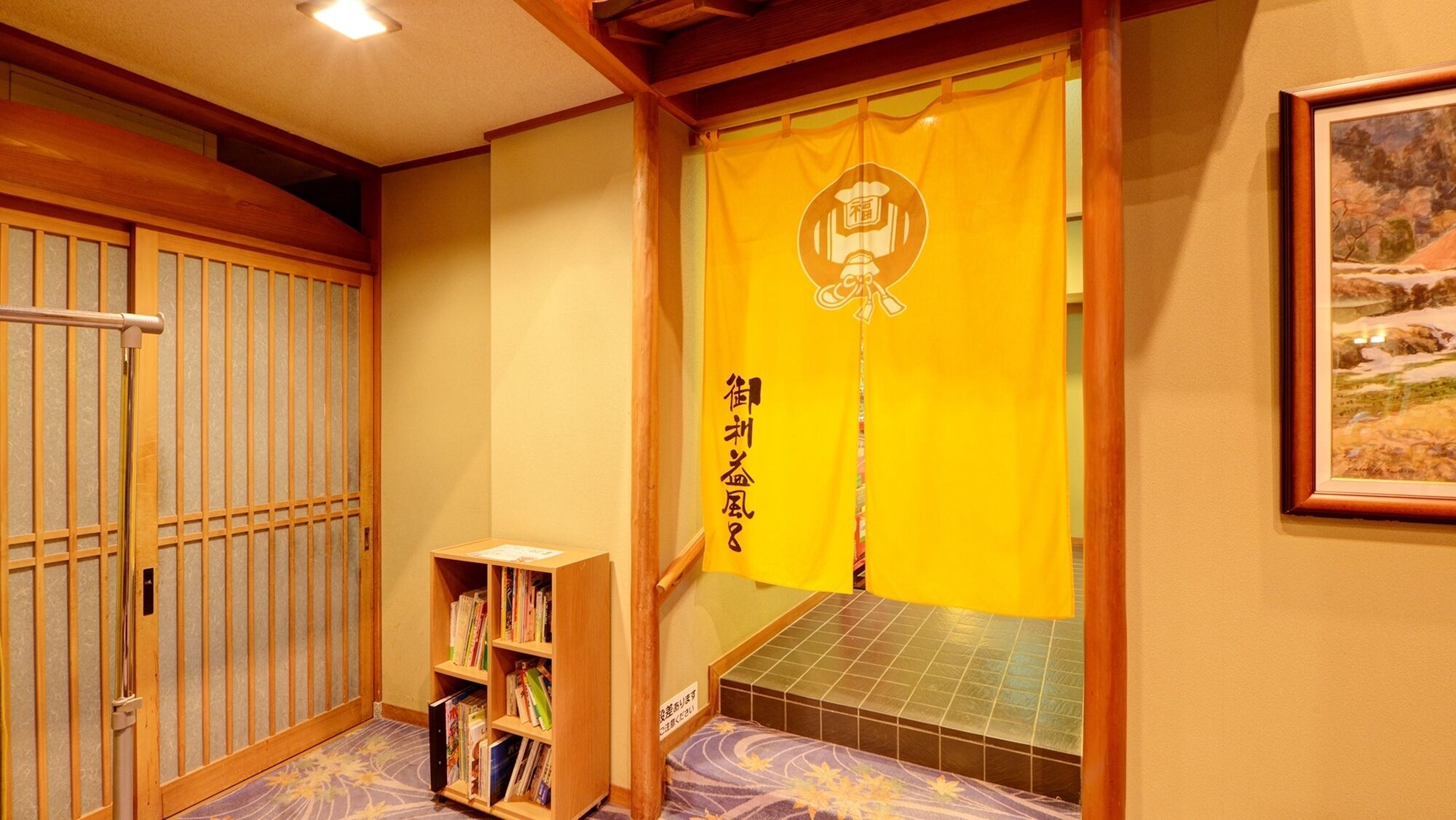 A traditional Japanese room with tatami flooring, a bookshelf, a futon bed, and a sliding door with a yellow curtain.