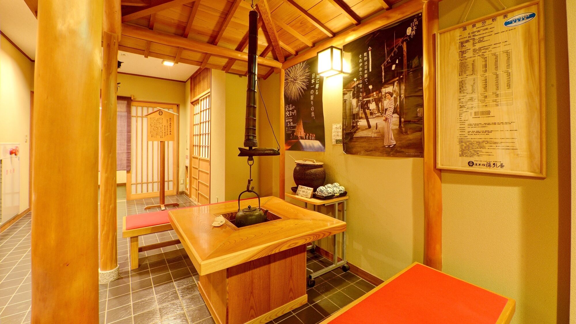 A traditional Japanese room with tatami flooring, a low wooden table, a hanging lantern, and a poster on the wall.