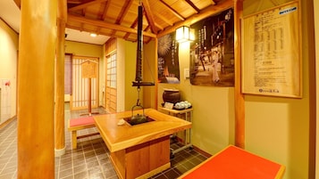 Una habitación japonesa tradicional con suelo de tatami, una mesa de madera baja, un farol colgante y un póster en la pared.