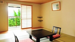 Ett traditionellt japanskt rum med tatamimattor på golvet, ett lågt bord och en skjutdörr som leder ut till en balkong.