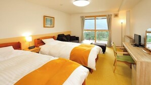 Ett hotellrum med två sängar, ett skrivbord med en dator, en stol och ett fönster med utsikt.