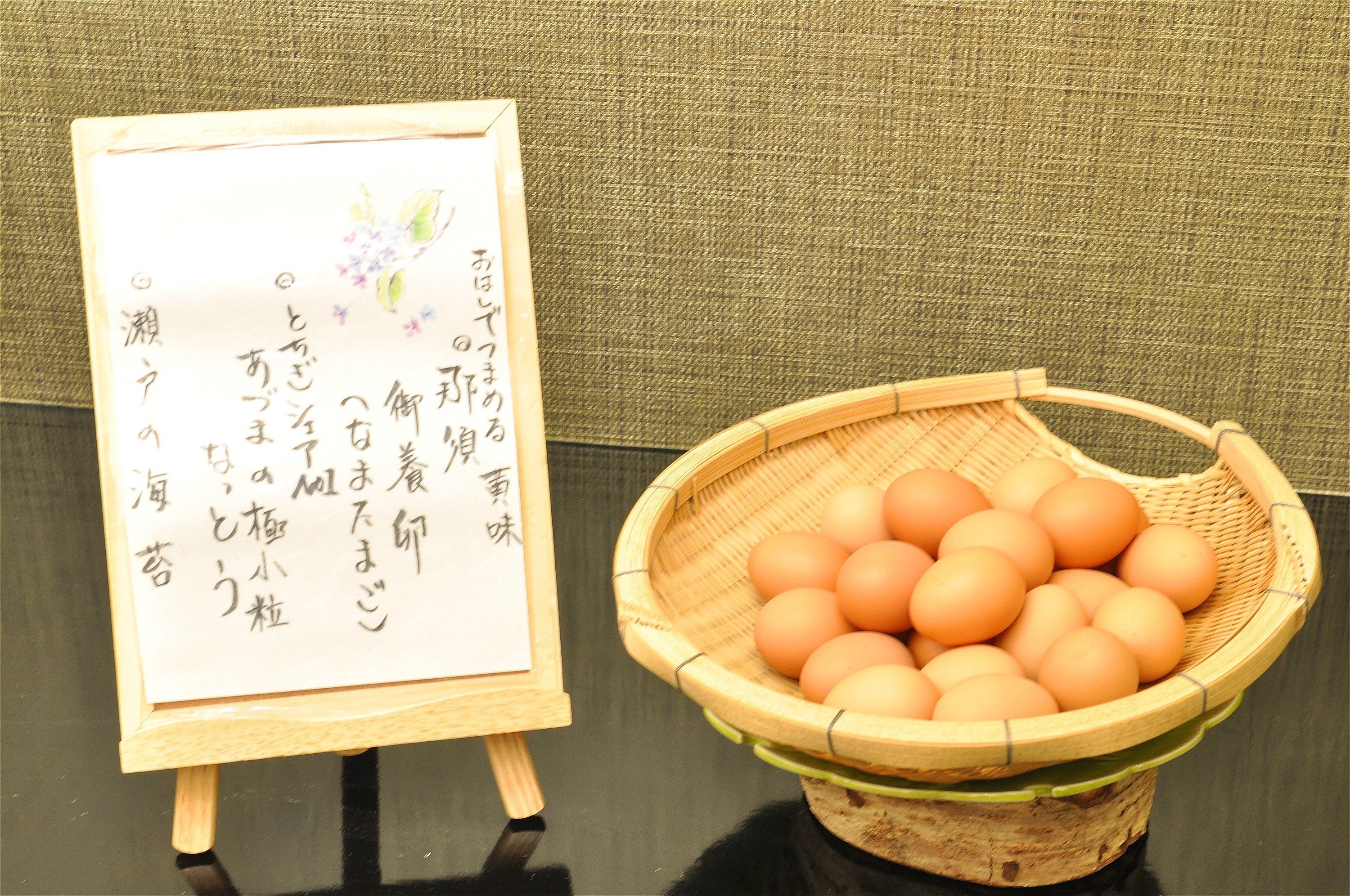 A wooden easel with a framed piece of paper and a basket of eggs.