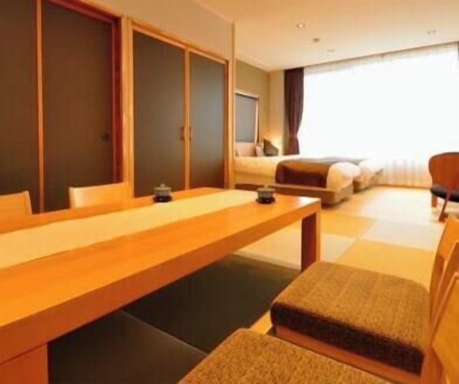 Une chambre d’hôtel avec un bureau en bois, un canapé, un lit et une grande fenêtre.