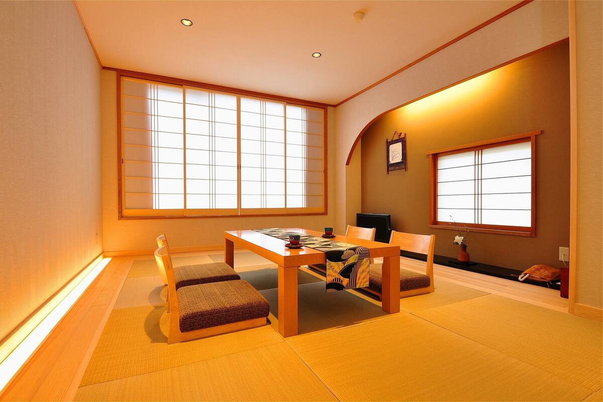 A traditional Japanese room with tatami flooring, a low table, and sliding doors.