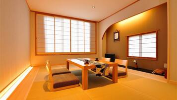 Una habitación japonesa tradicional con suelo de tatami, una mesita baja y puertas correderas.