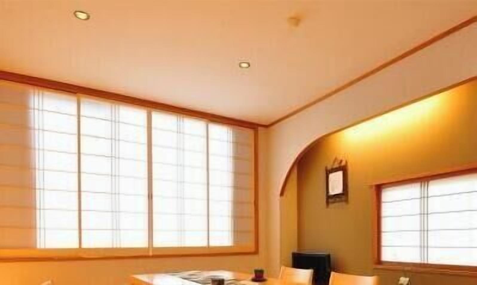 Une chambre d’hôtel avec de grandes fenêtres, un bureau et une chaise.