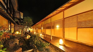 A traditional Japanese building with a stone pathway, lanterns, and a small water feature.