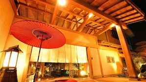 A traditional Japanese building with a wooden structure, a red umbrella, and a lantern.