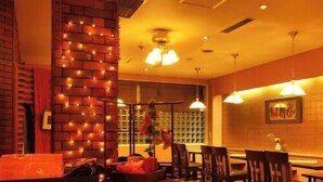 Ein Restaurantinneres mit Ziegelwänden, hängenden Lampen, Holztischen und -stühlen.