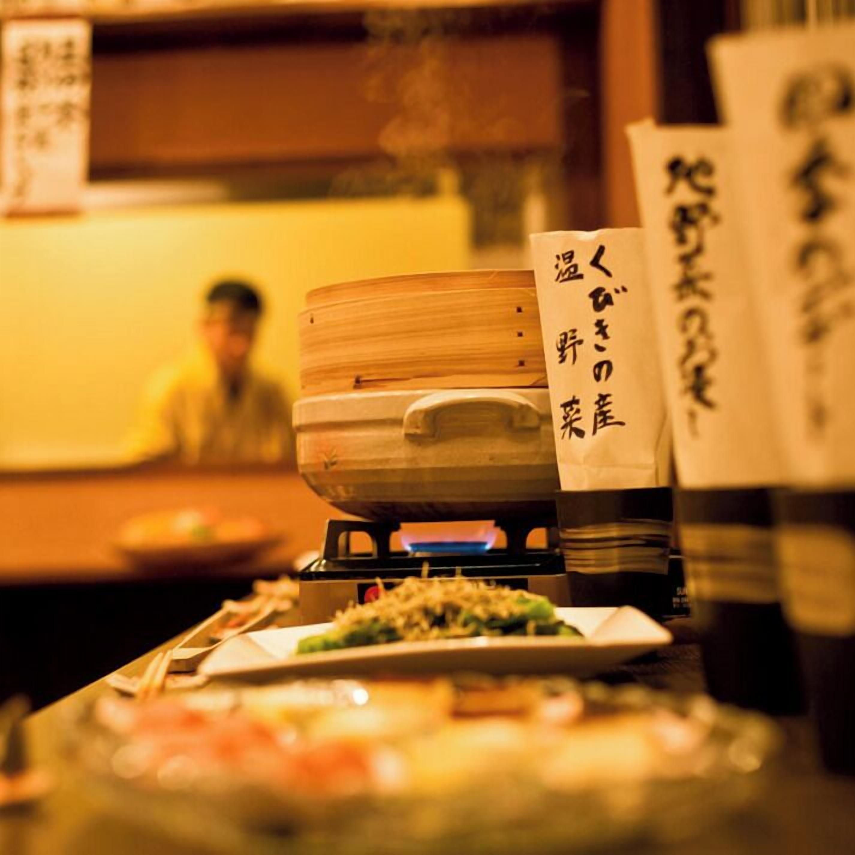 Een restaurantinterieur met een traditionele Japanse inrichting, inclusief een houten tafel met gerechten en een bordje dat een vegetarische optie aangeeft.