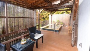 A covered outdoor area with a wooden deck, a hot tub, and wicker furniture. - Shiobara Onsen Yuyado Umekawaso (Nasushiobara)