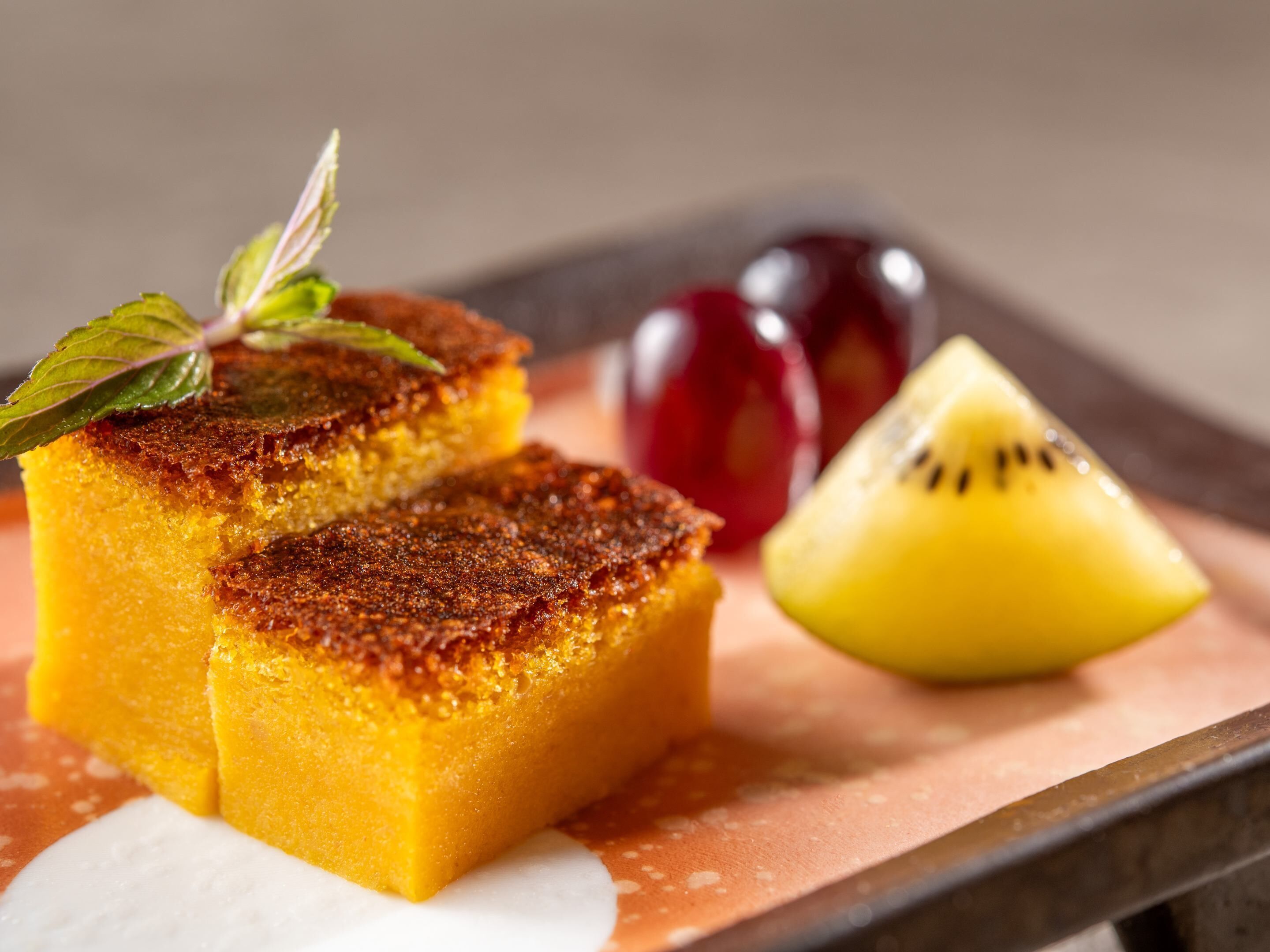 A dessert with a golden crust, accompanied by a slice of kiwi and a cherry.
