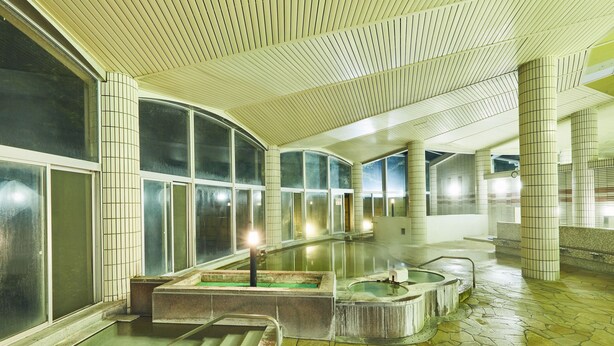 Un espace spa doté de grandes fenêtres, d’un sol en pierre et de plusieurs bains à remous.