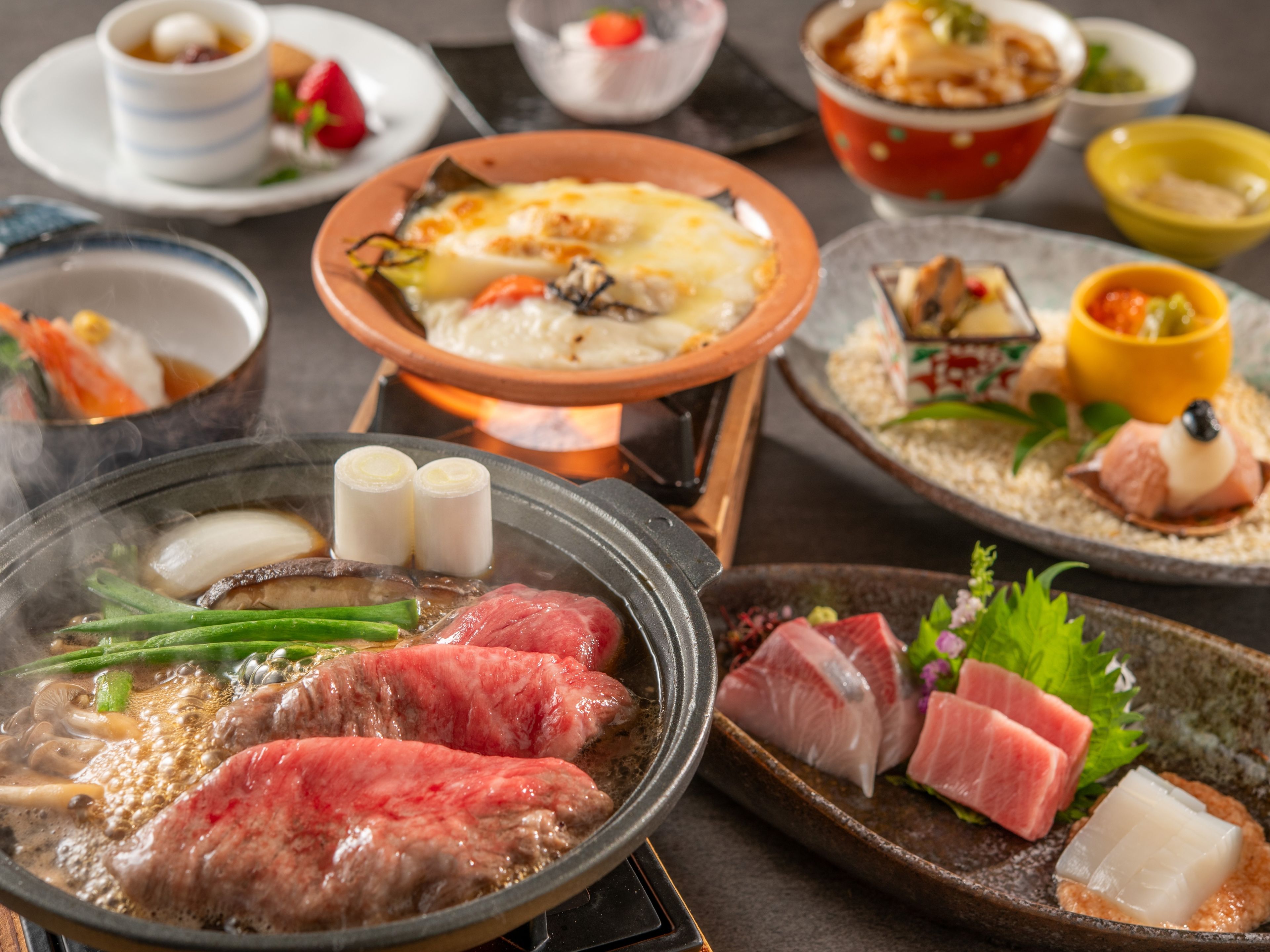 Forskellige retter, heriblandt en varm gryderet med kød og grøntsager, sashimi og anden japansk mad.