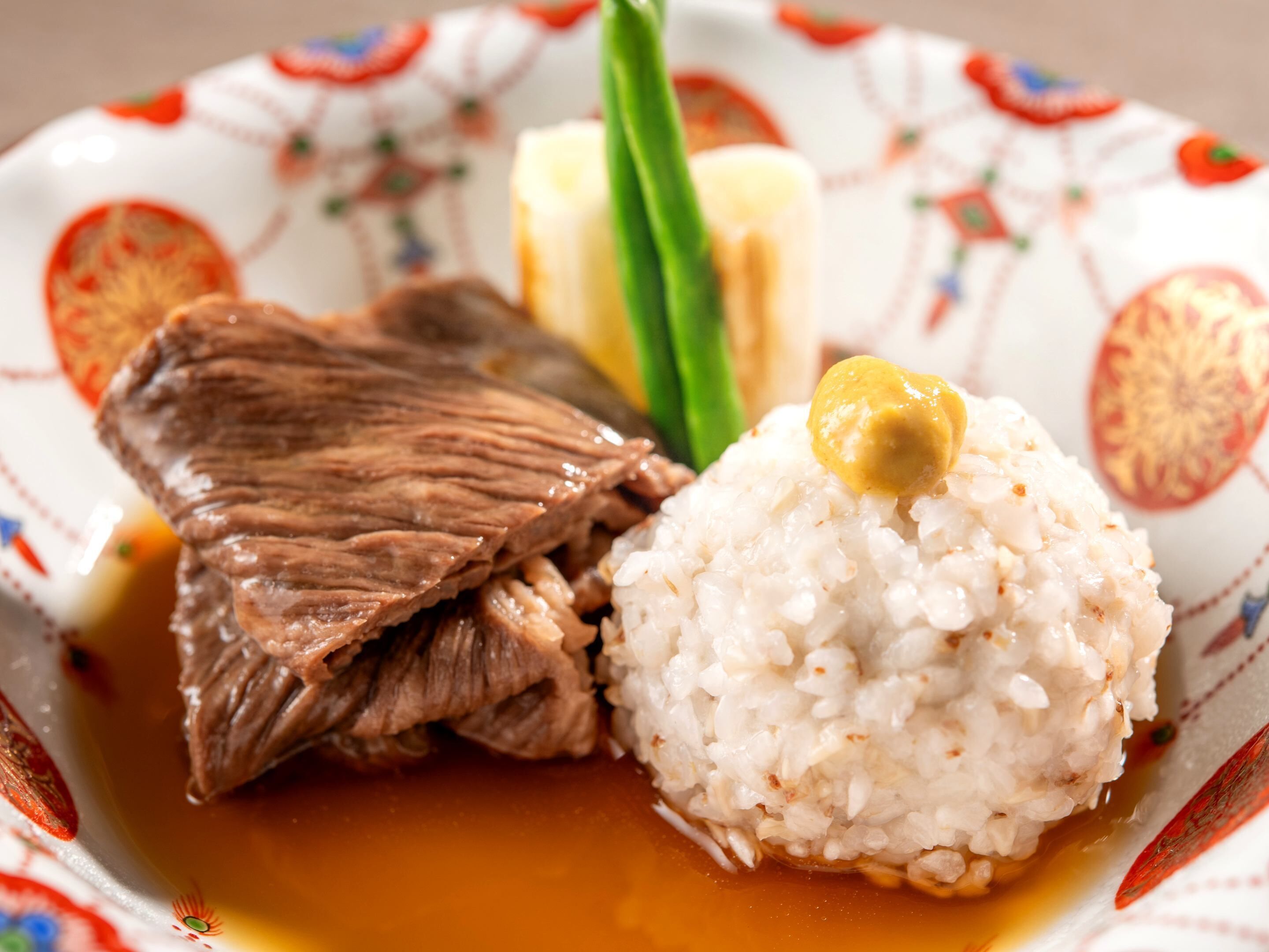 A plate with a piece of meat, rice, and a dollop of sauce.