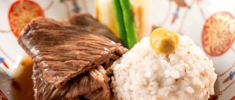 A plate with a piece of meat, rice, and a dollop of sauce.