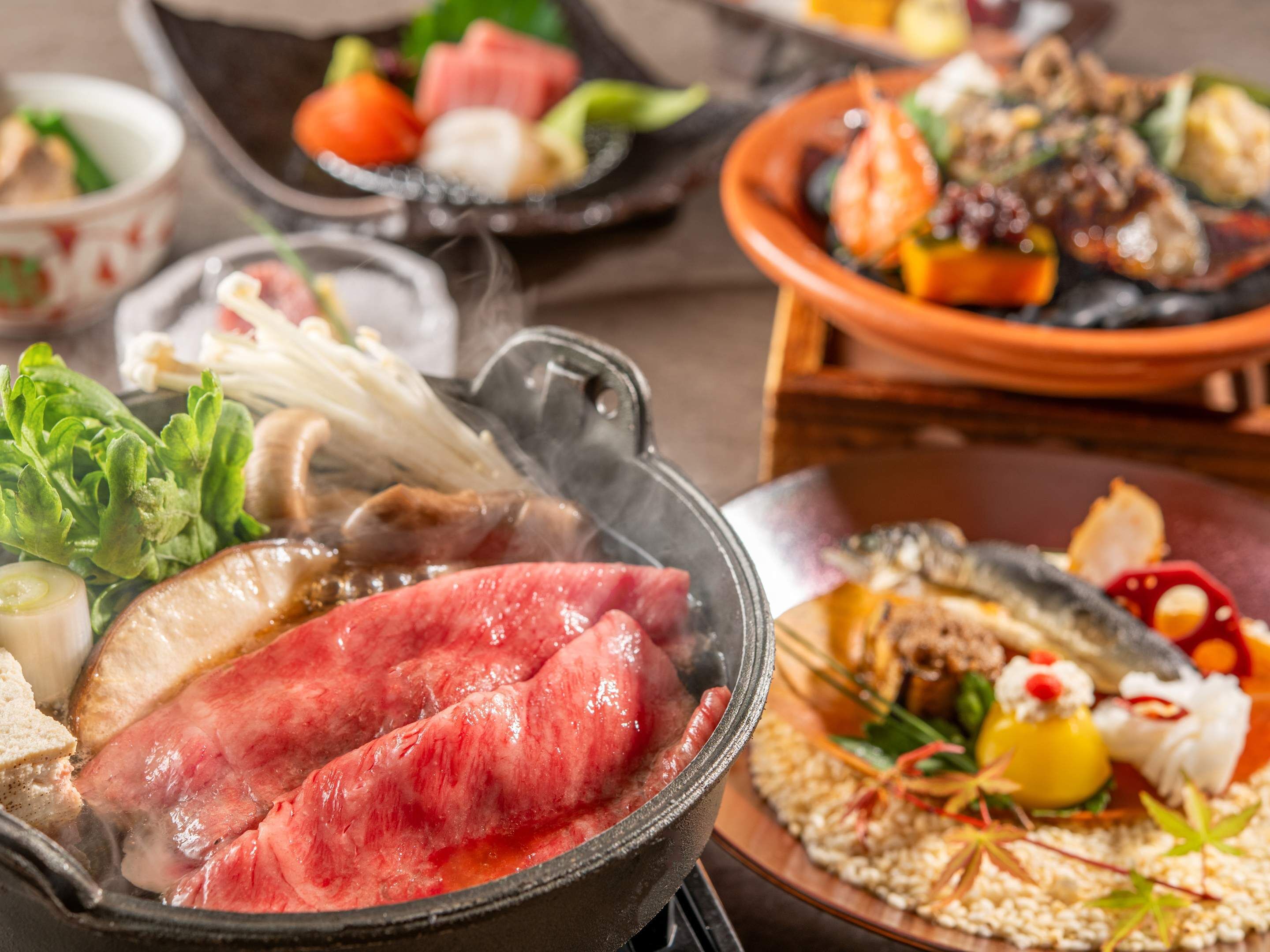 Diverse pietanze tra cui un hot pot, sashimi e una ciotola di riso.