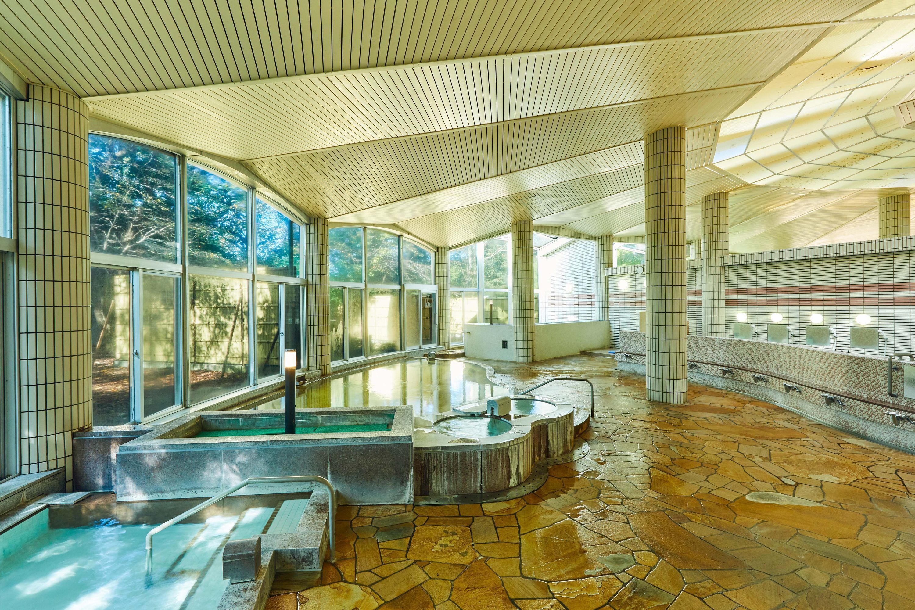 A modern spa with a stone floor, large windows, and a curved ceiling.