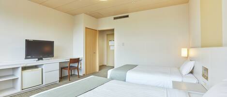 A hotel room with two beds, a desk with a television, and a chair.