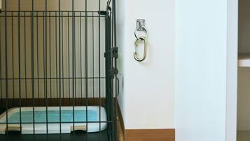 A pet kennel with a metal gate and a metal latch on the wall.