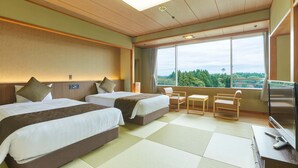 Une chambre d’hôtel avec deux lits, une télévision, un bureau et une grande fenêtre donnant sur l’extérieur.