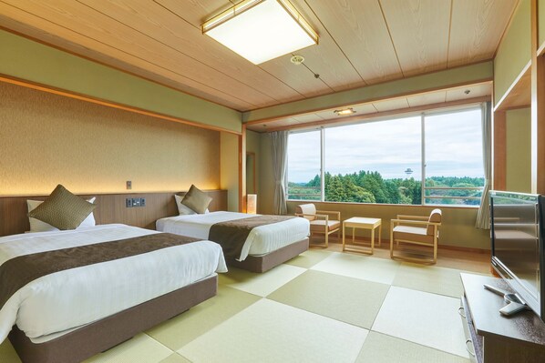 A hotel room with two beds, a TV, a desk, and a large window offering a view of the outdoors. - Kamenoi Hotel Kitsuregawa (Sakura)