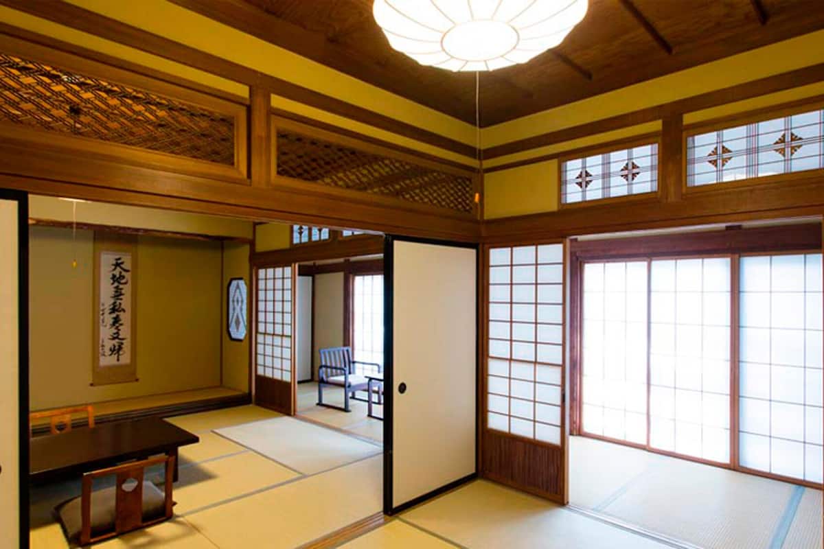 A traditional Japanese room with tatami flooring, sliding doors, and a ceiling fan.