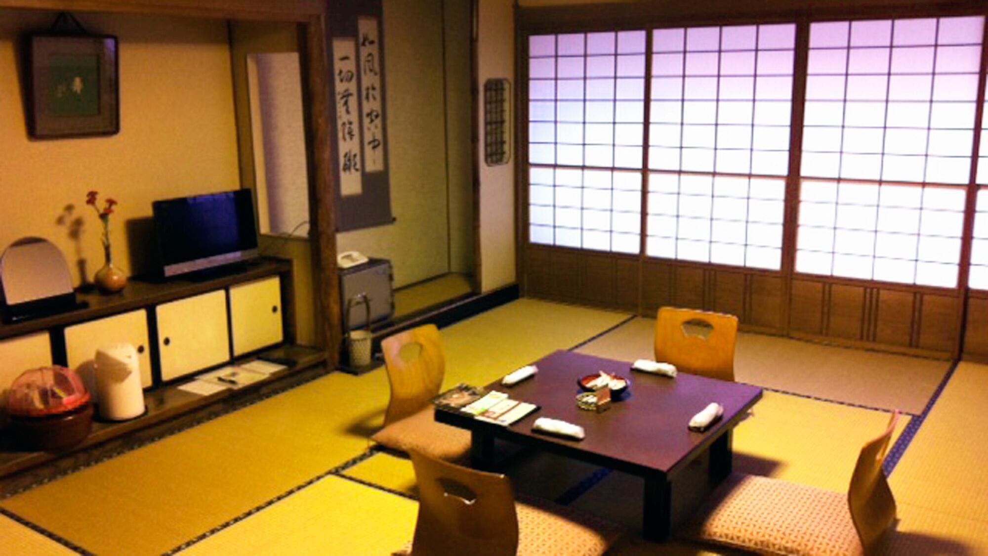 Een traditionele Japanse kamer met tatami vloerbedekking, een lage tafel en een televisie.