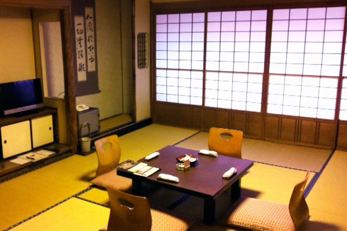 A traditional Japanese room with tatami flooring, a low table, and a television.